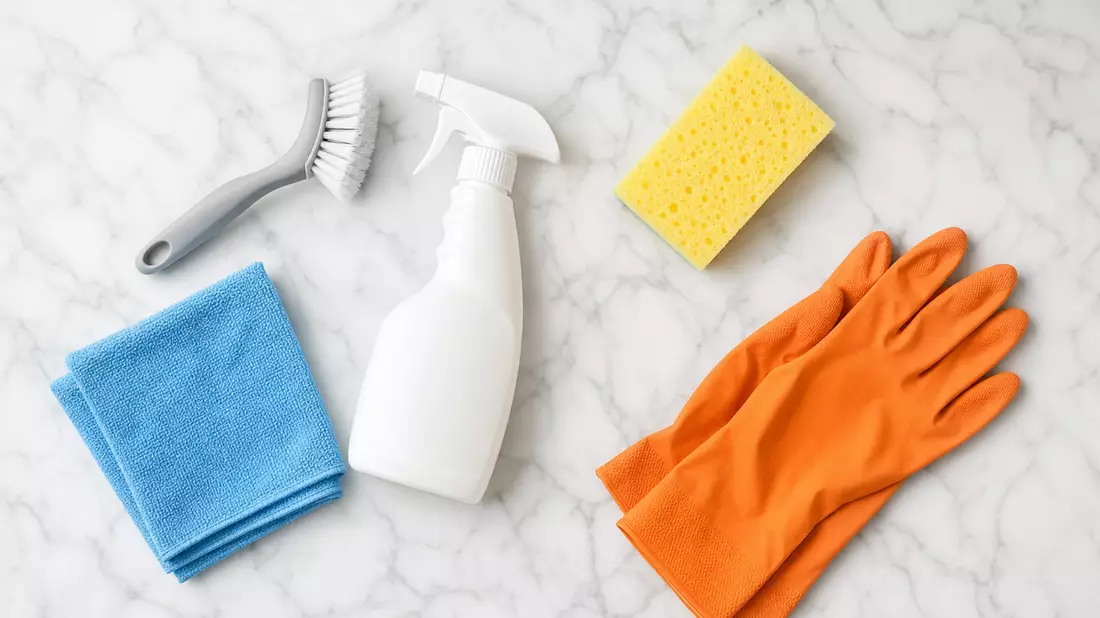 Flatlay-Draufsicht auf Reinigungsutensilien: Sprühflasche, Bürste, Mikrofasertuch, Schwamm und Hands