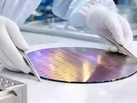 Fotorealistisches Reinraumbild zeigt einen Silizium-Wafer mit irisierendem Lichtspiel, der von behandschuhten Händen mit Pinzetten gehalten wird – ein zentrales Produktionsmotiv der Halbleiterindustrie, wie sie Infineon Technologies AG (ISIN DE0006231004) betreibt - Foto: THN