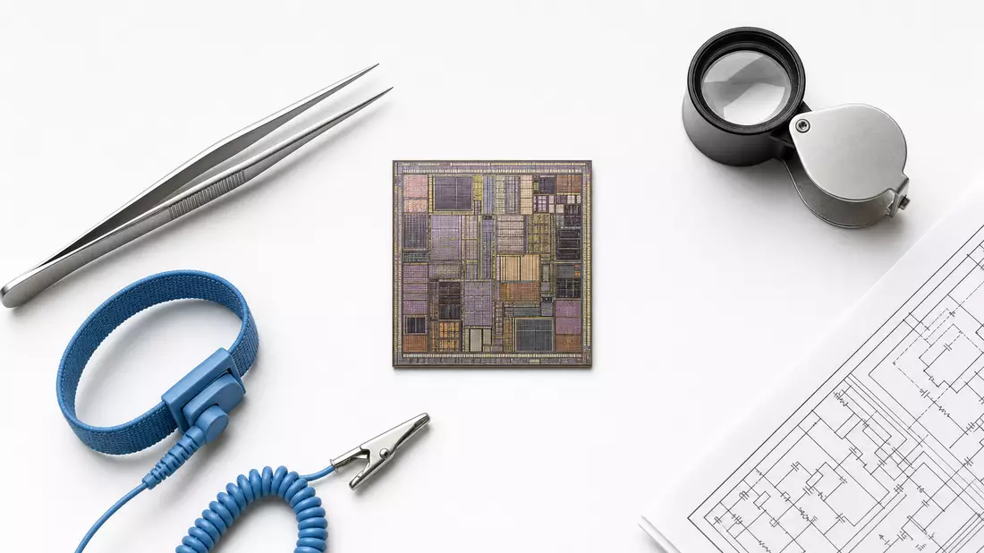 Flatlay mit Mikrochip, Pinzette, antistatischem Armband, Lupe und Schaltplan