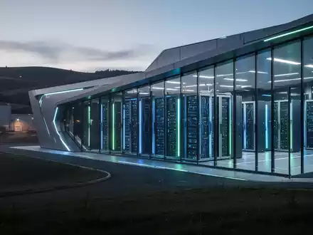 Futuristisches Rechenzentrum in der Dämmerung, blaue und grüne Lichter im Inneren, Symbol für KI und Technologie. - Foto: über boerse-global.de