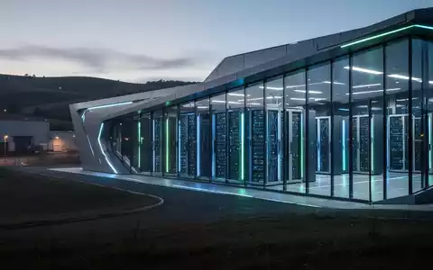 Futuristisches Rechenzentrum in der Dämmerung, blaue und grüne Lichter im Inneren, Symbol für KI und Technologie. - Foto: über boerse-global.de