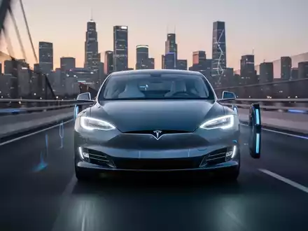 Ein futuristisches, elegantes Tesla-Auto fährt autonom auf einer modernen Autobahn bei Dämmerung, die Scheinwerfer leuchten. - Foto: über boerse-global.de
