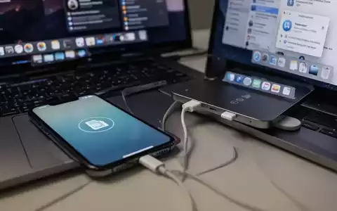 Ein iPhone, das per USB-C-Kabel mit einem MacBook Pro verbunden ist, zeigt ein Dateiübertragungssymbol auf dem Bildschirm. - Foto: über boerse-global.de