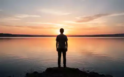 Eine Person steht bei Sonnenaufgang an einem ruhigen See und blickt auf den Horizont, symbolisch für Neuanfänge und Selbstverbesserung. - Foto: über boerse-global.de
