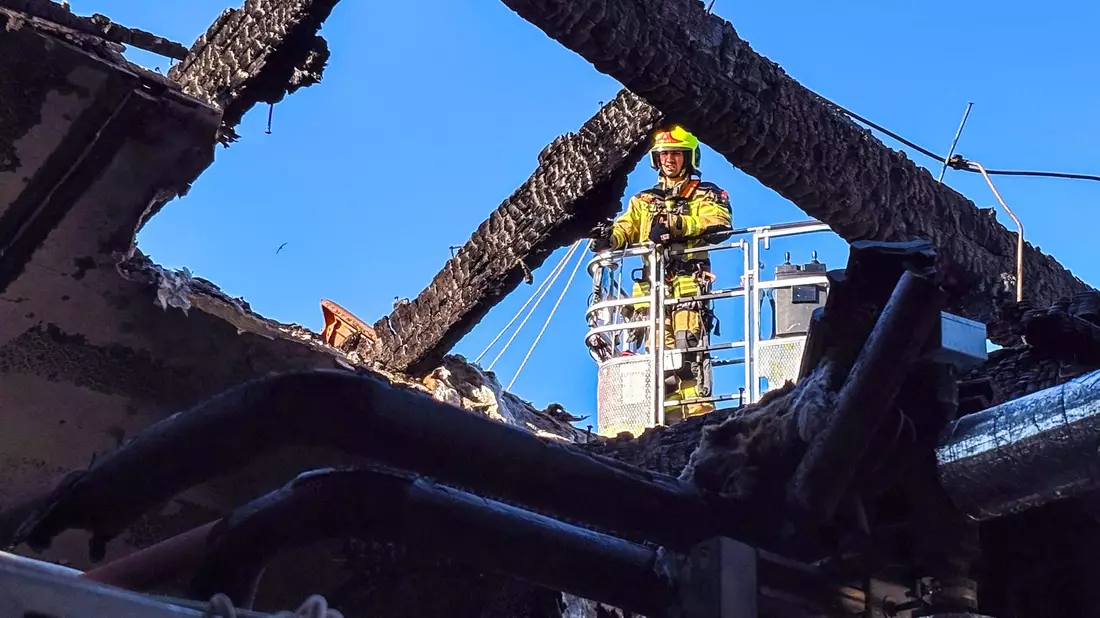 Ein Feuerwehrmann untersucht von einer Drehleiter aus den ausgebrannten Dachstuhl. (Handoutbild) - Bild: Landkreis Ludwigslust-Parchim/dpa