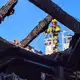 Ein Feuerwehrmann untersucht von einer Drehleiter aus den ausgebrannten Dachstuhl. (Handoutbild) - Bild: Landkreis Ludwigslust-Parchim/dpa