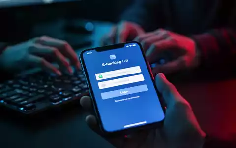 Nahaufnahme eines Smartphone-Bildschirms, der eine gefälschte E-Banking-Anmeldeseite zeigt, mit unscharfen Händen im Hintergrund. - Foto: über boerse-global.de