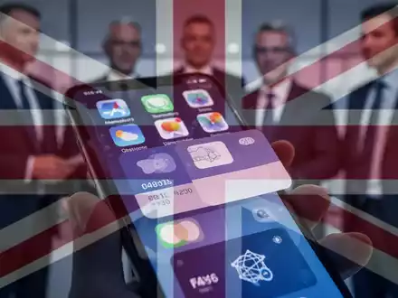 Smartphone-Bildschirm mit App-Icons und Zahlungsoberfläche, dezenter UK-Flaggen-Overlay, unscharfe Figuren im Hintergrund. - Foto: über boerse-global.de