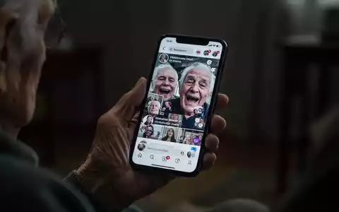 Eine ältere Hand hält ein Smartphone, dessen Bildschirm verzerrte Gesichter oder einen chaotischen Social-Media-Feed widerspiegelt. - Foto: über boerse-global.de