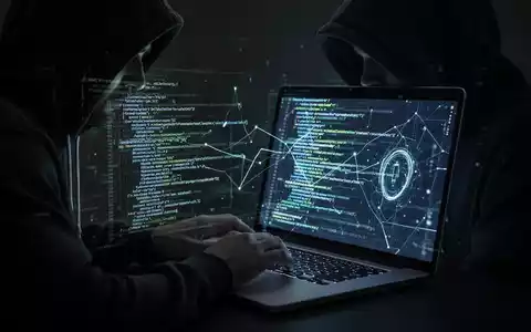 Verschattete Gestalt in Kapuzenjacke tippt auf Laptop, komplexer Code leuchtet auf dem Bildschirm, symbolisiert Cybersicherheitsbedrohungen. - Foto: über boerse-global.de