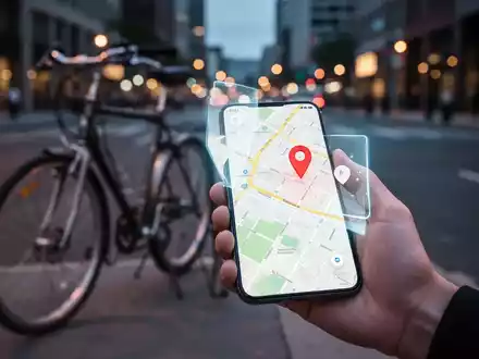 Eine Hand hält ein Smartphone, das eine Karte mit einem Ortungs-Pin anzeigt, im Hintergrund ein Fahrrad auf einer Stadtstraße. - Foto: über boerse-global.de
