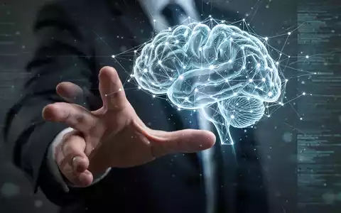 Eine menschliche Hand greift nach einem leuchtenden, abstrakten digitalen Gehirnnetzwerk, das die Steuerung und Regulierung künstlicher Intelligenz symbolisiert. - Foto: über boerse-global.de