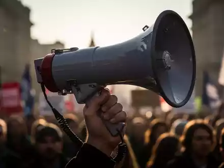 Nahaufnahme einer Hand, die ein Megafon hält, symbolisiert die Stimme der Gewerkschaften bei Protesten gegen Regierungspolitik. - Foto: über boerse-global.de