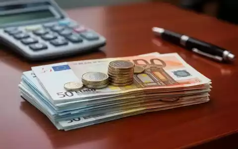 Ein Stapel Euro-Banknoten und Münzen auf einem Schreibtisch, mit einem Taschenrechner und Stift im unscharfen Hintergrund. - Foto: über boerse-global.de