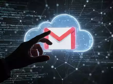 Eine schattenhafte Hand greift nach einem leuchtenden Gmail-Logo auf einem Bildschirm, umgeben von Code, symbolisiert eine Cyber-Bedrohung für Cloud-Konten. - Foto: über boerse-global.de