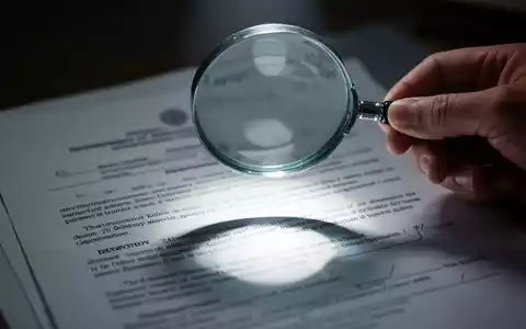 Eine Hand hält eine Lupe über ein verschwommenes Regierungsdokument, das Transparenz und staatliche Informationen symbolisiert. - Foto: über boerse-global.de