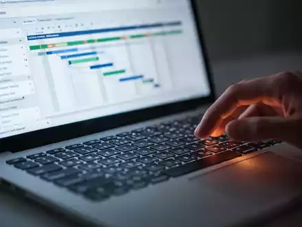 Nahaufnahme einer Laptop-Tastatur mit unscharfem Bildschirm, der Projektmanagement-Software zeigt. - Foto: über boerse-global.de