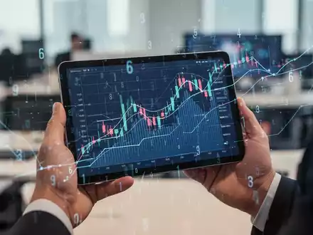 Hände halten ein Tablet mit Finanzgrafik und digitalen Overlays, die Steueränderungen darstellen. - Foto: über boerse-global.de
