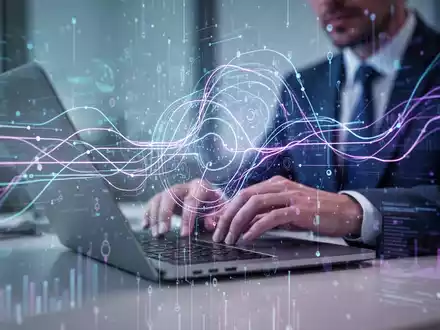 Leuchtendes, futuristisches Interface mit abstrakten Datenströmen über einer Person, die an einem Laptop arbeitet, symbolisiert KI-E-Mail-Verwaltung. - Foto: über boerse-global.de