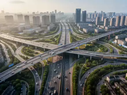 Eine Luftaufnahme einer modernen Autobahnkreuzung mit mehreren Ebenen und Brücken, umgeben von Stadtlandschaft und Grünflächen. - Foto: über boerse-global.de