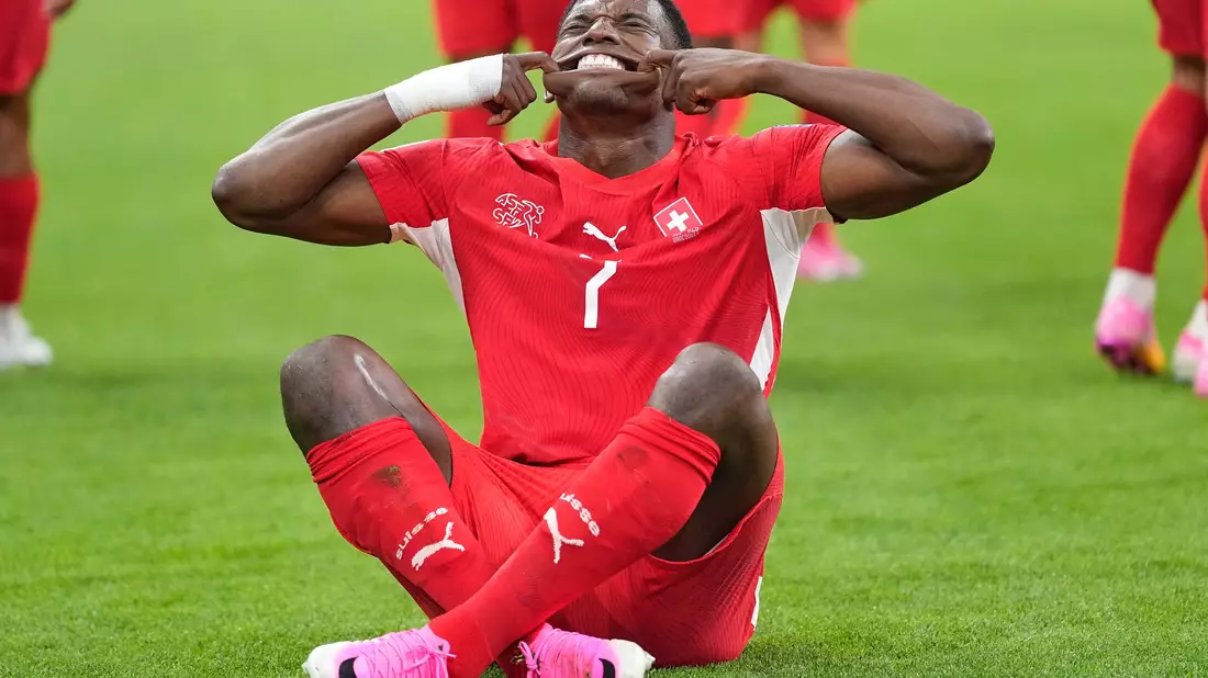 Bitte lächeln: Embolo jubelt im Sitzen. - Bild: Lindsey Wasson/AP/dpa