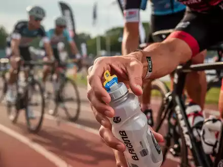 Nahaufnahme der Hand eines Triathleten, der während eines Rennens nach einem Energiegel oder einer Trinkflasche greift. - Foto: über boerse-global.de