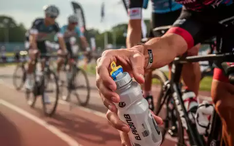 Nahaufnahme der Hand eines Triathleten, der während eines Rennens nach einem Energiegel oder einer Trinkflasche greift. - Foto: über boerse-global.de