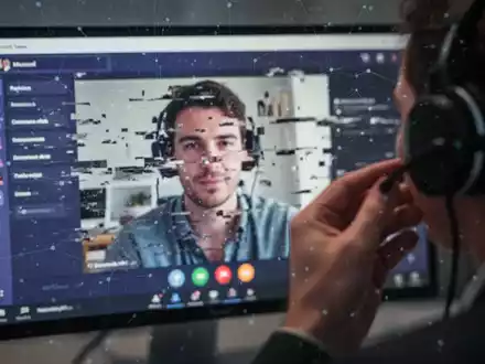 Nahaufnahme eines verschwommenen Computerbildschirms mit einer gestörten Microsoft Teams-Besprechung, im Vordergrund eine Hand, die ein Headset einstellt. - Foto: über boerse-global.de