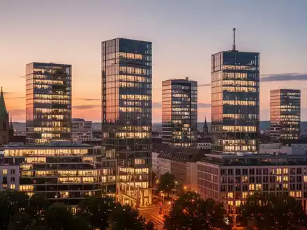 Moderne Bürogebäude in der Münchner Skyline bei Sonnenuntergang, beleuchtete Fenster, professionelle Fotografie. - Foto: über boerse-global.de