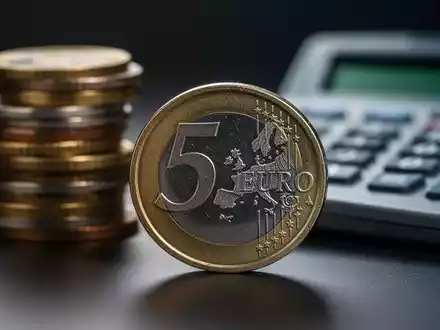Nahaufnahme einer deutschen 5-Euro-Münze, im Hintergrund verschwommen weitere Münzen und ein Taschenrechner. - Foto: über boerse-global.de