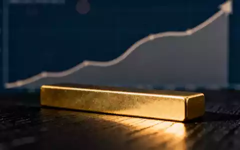 Ein glänzender Goldbarren ruht auf einer dunklen Fläche, im Hintergrund eine angedeutete aufwärts gerichtete Kurslinie. - Foto: über boerse-global.de