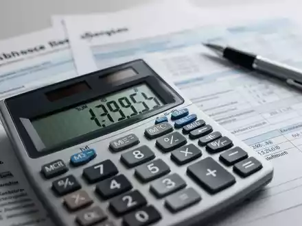 Ein Taschenrechner zeigt Finanzzahlen, im Hintergrund verschwommene Steuerdokumente und ein Stift. Symbolisiert neue Pauschbeträge und Steuerthemen. - Foto: über boerse-global.de
