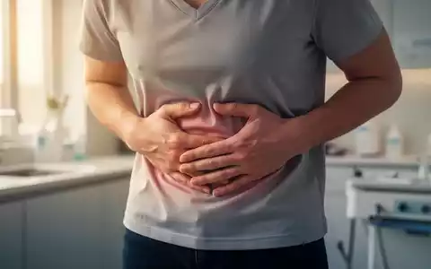 Eine Person hält sich den Bauch, um Beschwerden zu lindern, mit sanftem Licht, das durch ein Fenster fällt. - Foto: über boerse-global.de