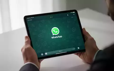 Hände halten ein iPad mit WhatsApp-Chat-Oberfläche, unscharfer Hintergrund deutet auf Konnektivität und Unabhängigkeit hin. - Foto: über boerse-global.de