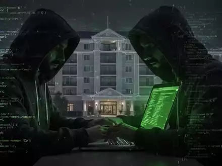 Person in Kapuzenjacke tippt auf Laptop, digitaler Code und Hotelumriss im Hintergrund, symbolisiert Cyberkriminalität gegen Hotels. - Foto: über boerse-global.de