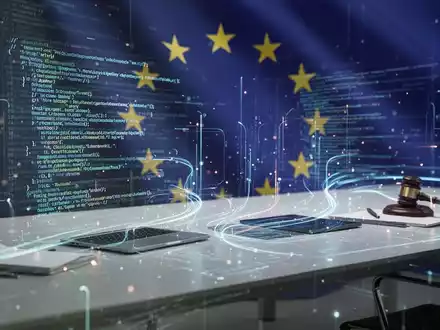 Digitale Compliance-Linien und Datenfluss über futuristischem Schreibtisch mit dezentem EU-Flaggenmotiv im Hintergrund, das KI-Regulierung darstellt. - Foto: über boerse-global.de