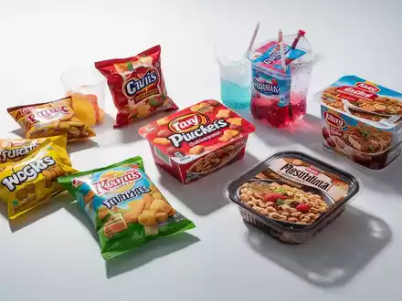 Nahaufnahme von ultra-verarbeiteten Lebensmitteln wie bunten Snacks und Zuckergetränken auf weißem Hintergrund, die künstliche Natur hervorhebend. - Foto: über boerse-global.de