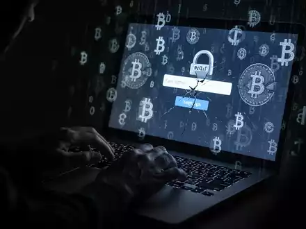 Eine Nahaufnahme von Händen, die auf einer Tastatur tippen, mit einem Bildschirm, der verzerrte Kryptowährungssymbole und eine gefälschte Anmeldeseite zeigt. - Foto: über boerse-global.de