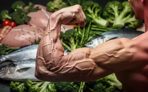 Ein muskulöser Arm, der einen Bizeps flexen lässt, mit unscharfem Hintergrund aus gesunden Lebensmitteln wie Hähnchenbrust und Gemüse. - Foto: über boerse-global.de