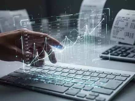 Eine Hand interagiert mit einem leuchtenden holografischen Tabellenblatt über einer Tastatur, das automatisierte Finanzdatenverarbeitung symbolisiert. - Foto: über boerse-global.de