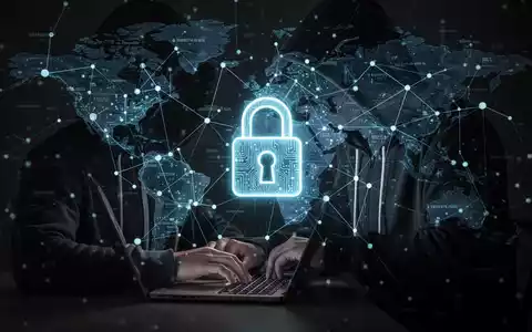 Verschwommene Gestalt in Kapuzenjacke tippt auf Laptop, darüber leuchtendes digitales Vorhängeschloss über globalen Datenpunkten. - Foto: über boerse-global.de