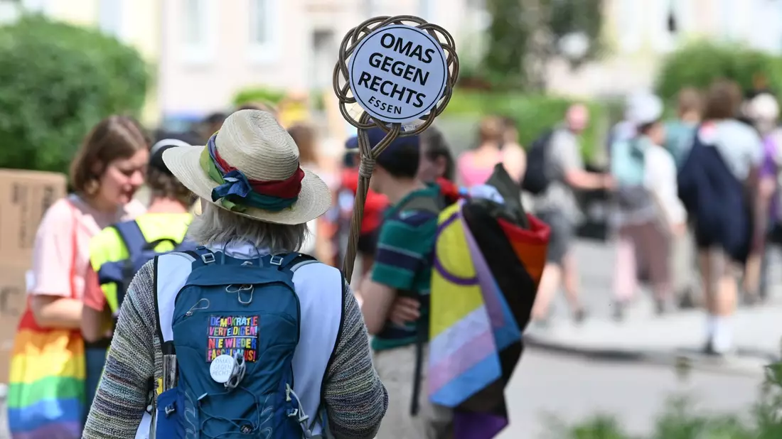 Eine Demonstrantin hält ein Schild von «Omas gegen Rechts» in die Höhe. - Bild: Heiko Rebsch/dpa