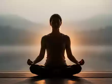 Eine Person sitzt in meditativer Pose, umgeben von sanftem Licht, das Ruhe und Achtsamkeit symbolisiert. - Foto: über boerse-global.de