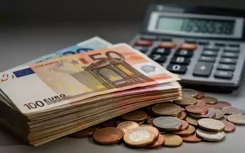 Ein Stapel Euro-Banknoten, teilweise verdeckt von Kleingeld, mit einem Taschenrechner im unscharfen Hintergrund, der steigende Zahlen anzeigt. - Foto: über boerse-global.de