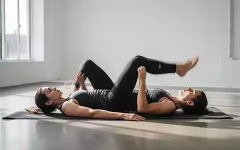 Eine Person führt eine Rückenlage-Übung auf einer Yogamatte in einem hellen, minimalistischen Studio aus. - Foto: über boerse-global.de