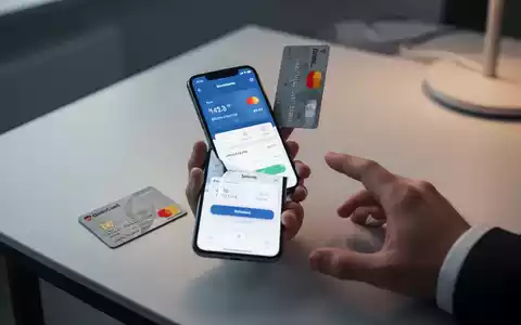 Eine Hand hält ein Smartphone mit Zahlungs-App, daneben eine deutsche Girocard auf einem modernen Tisch – Symbol für digitales Bezahlen. - Foto: über boerse-global.de