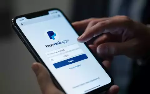 Nahaufnahme eines Smartphone-Bildschirms mit gefälschter PayPal-Anmeldeseite, Hand darüber schwebend, digitaler Betrug. - Foto: über boerse-global.de