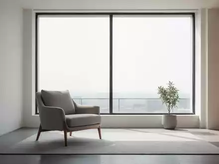 Ein minimalistisch eingerichtetes Wohnzimmer mit viel Freiraum, einem Sessel und einem Fenster, das Tageslicht hereinlässt. - Foto: über boerse-global.de