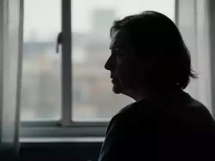 Eine einzelne, silhouettierte Person schaut nachdenklich aus einem Fenster, die Umgebung ist unscharf. Die Szene wirkt ruhig und kontemplativ. - Foto: über boerse-global.de