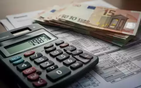 Nahaufnahme eines Taschenrechners mit Euro-Banknoten und einem Rentenbescheid im Hintergrund, der finanzielle Berechnungen darstellt. - Foto: über boerse-global.de